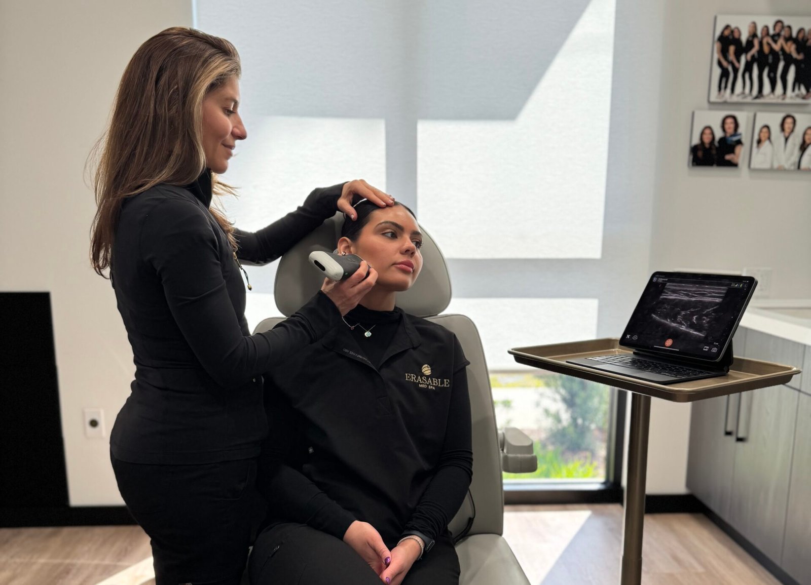 Laura Osterweil performing an ultrasound-guided facial consultation on a female patient, holding a probe near the jawline area.